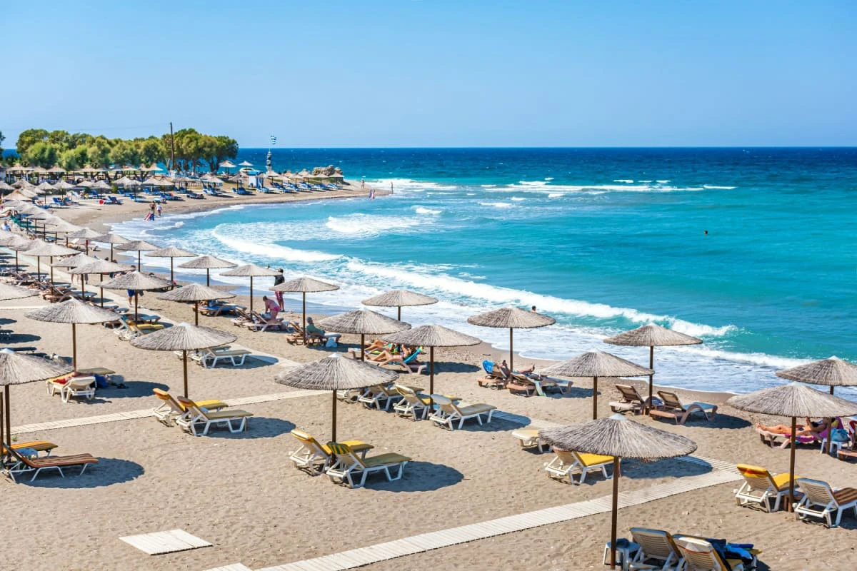 Plaja cu oameni, umbrele si sezlonguri langa orasul antic Kamiros (Rhodos, Grecia)