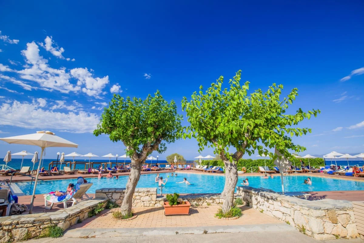 resort cu piscina, copaci, oameni in apa si mare pe fundal, in Hersonissos
