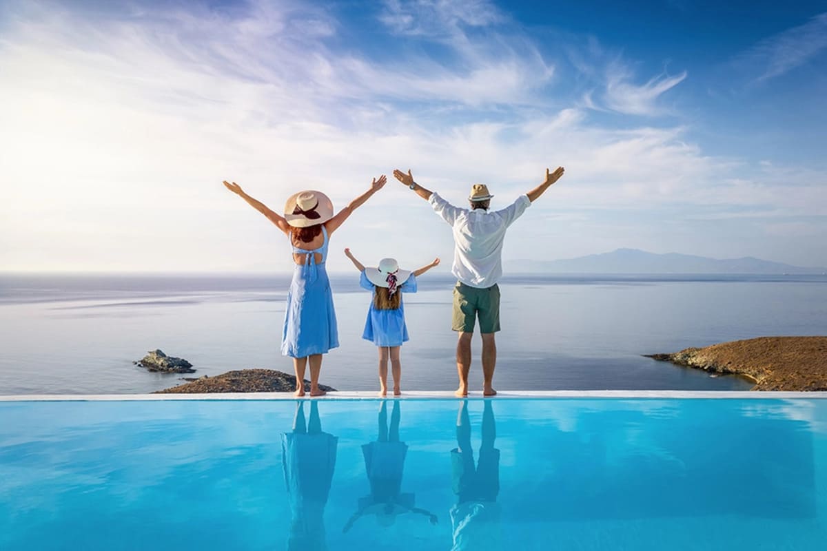 Familie cu un copil admirand marea de la piscina unui resort in timpul vacantei