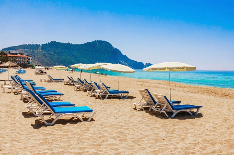 Plaja Cleopatra din Antalya, cu șezlonguri albastre și umbrele crem