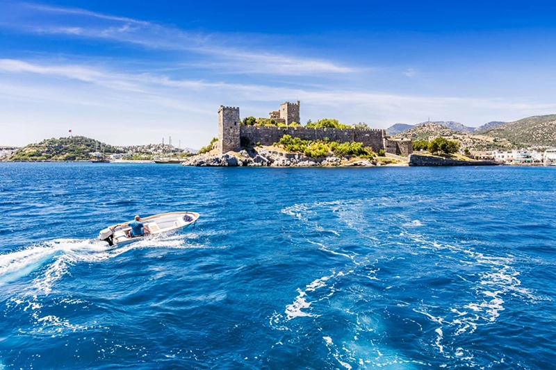 bărbat cu barca pe mare, în fața castelului Bodrum