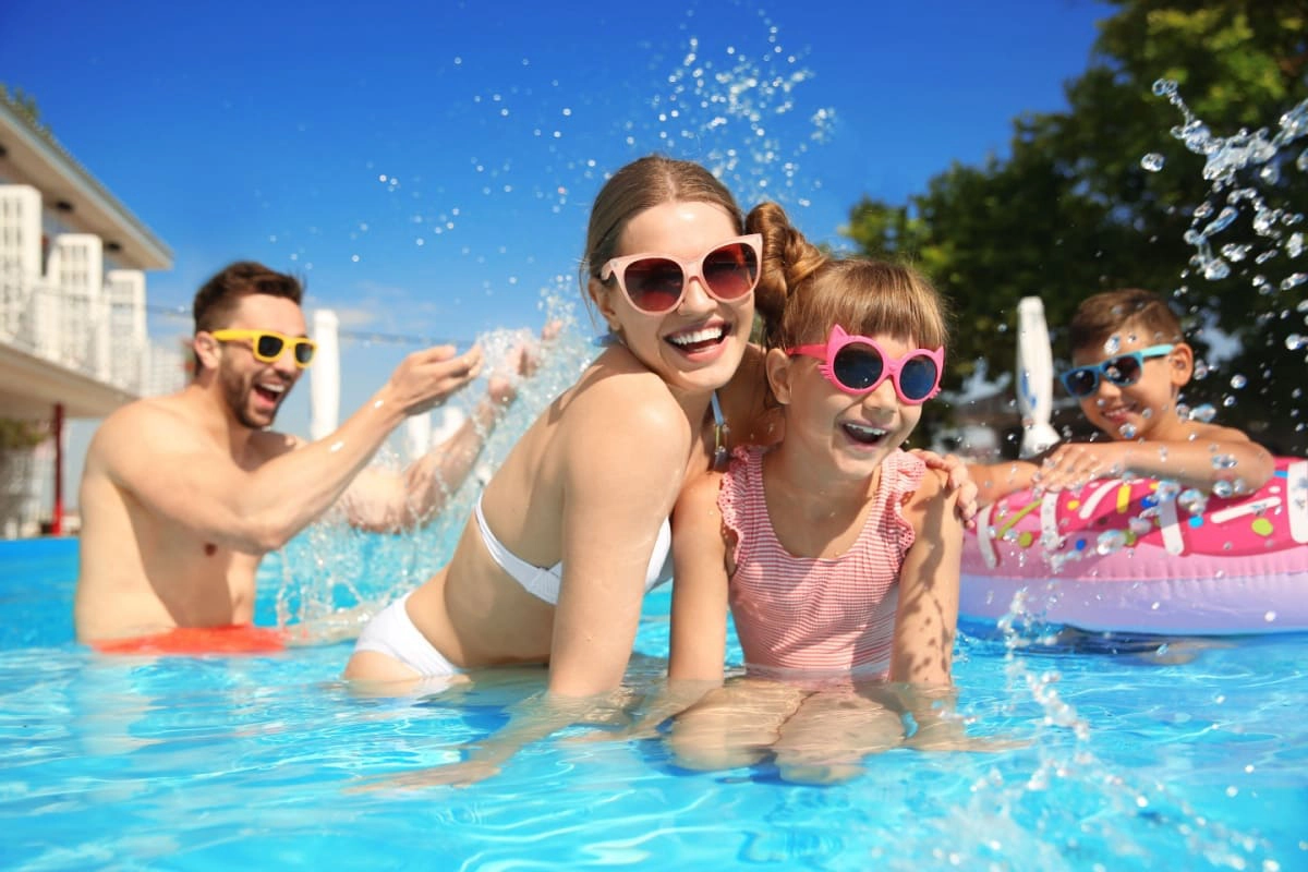 familie formata din mama, tata, fata si baiat se distreaza intr-o piscina