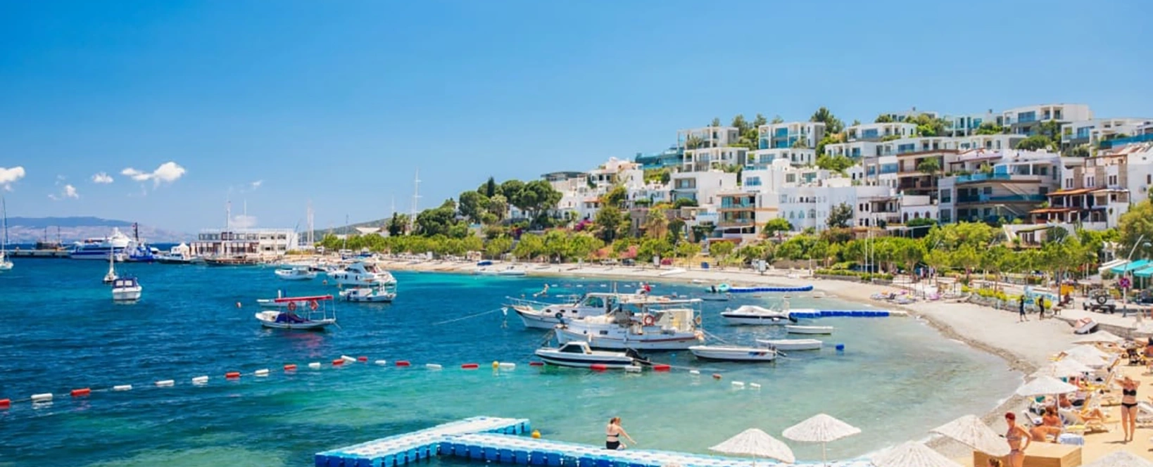 vedere panoramică asupra litoralului din Bodrum, cu persoane pe plajă, iahturi, case