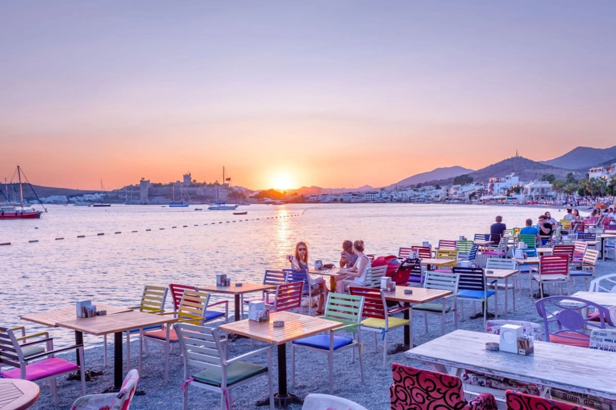 oameni la mese pe litoralul portului Bodrum la apus