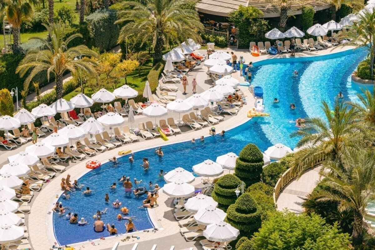 persoane care inoata, fac plaja si alte activitati la piscina unui resort din Antalya